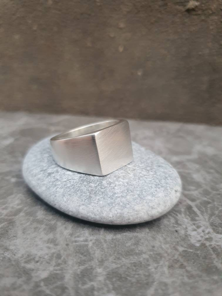 Silver ring on a textured stone surface with a neutral background
