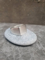 Silver ring on a textured stone surface with a neutral background