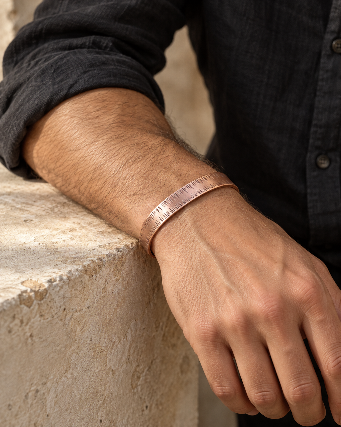 Close-up of the textured copper cuff on a male model's wrist
