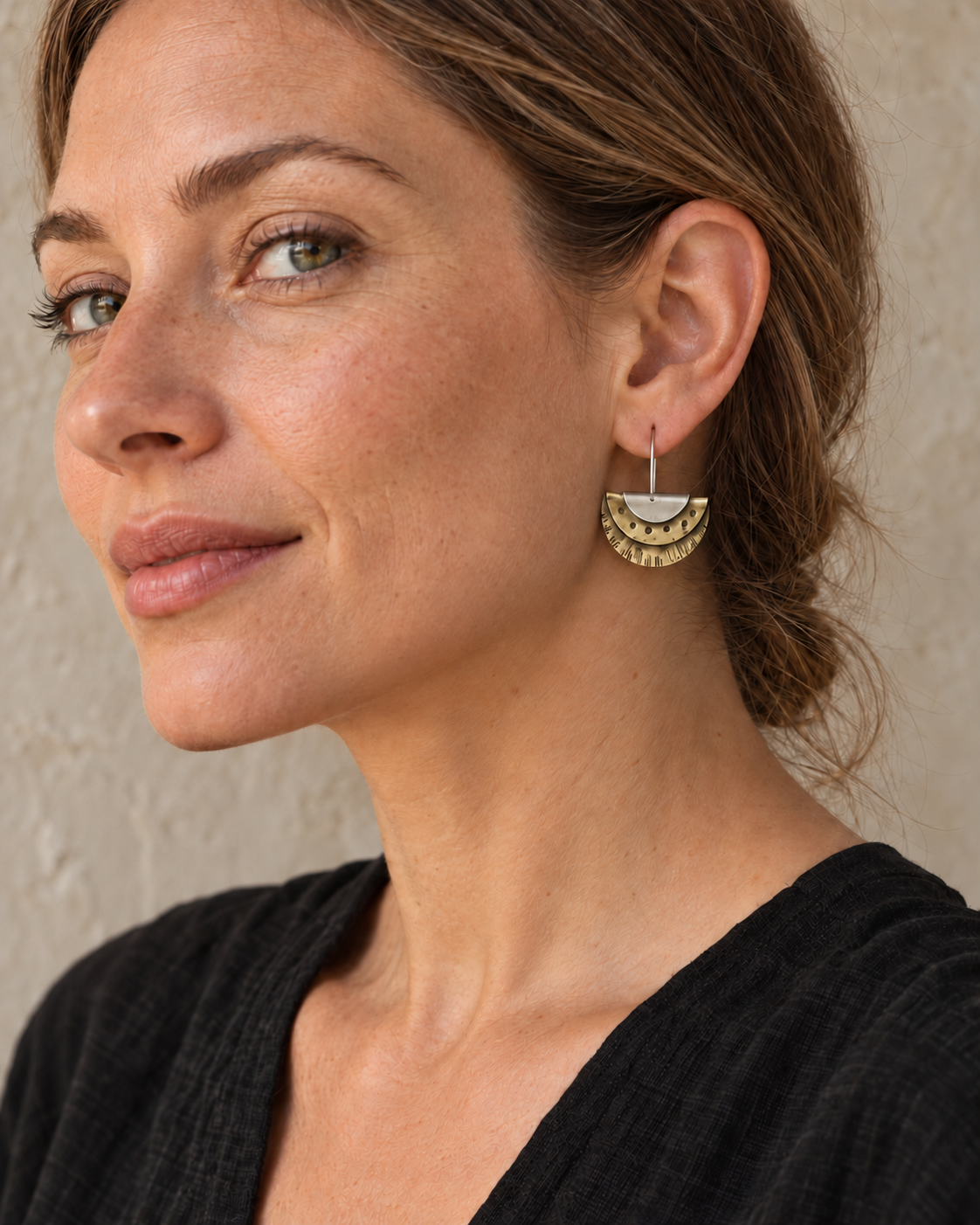 Brass and silver layered fan earring with centered sterling silver ear wire worn by a model, showing scale against the face