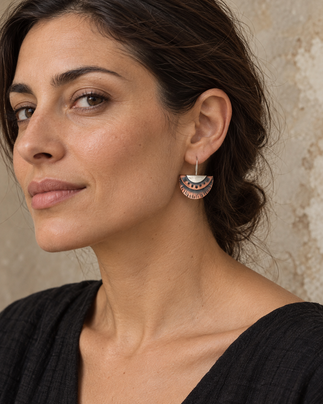 Copper and silver layered fan earring worn by a brunette model, showing its scale against the face