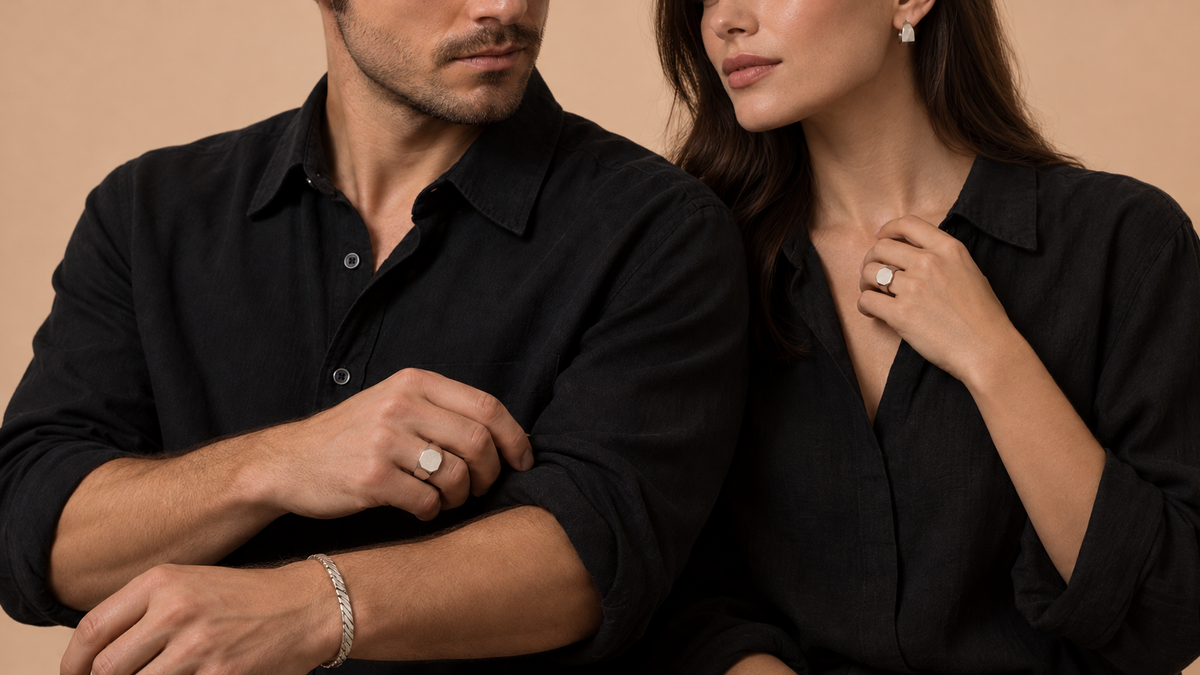 Woman and man in black linen wearing silver signet rings, a silver cuff and sculptural earrings.