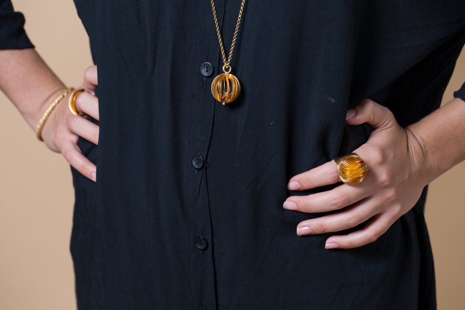 Sculptural pendant and ring worn with a dark shirt