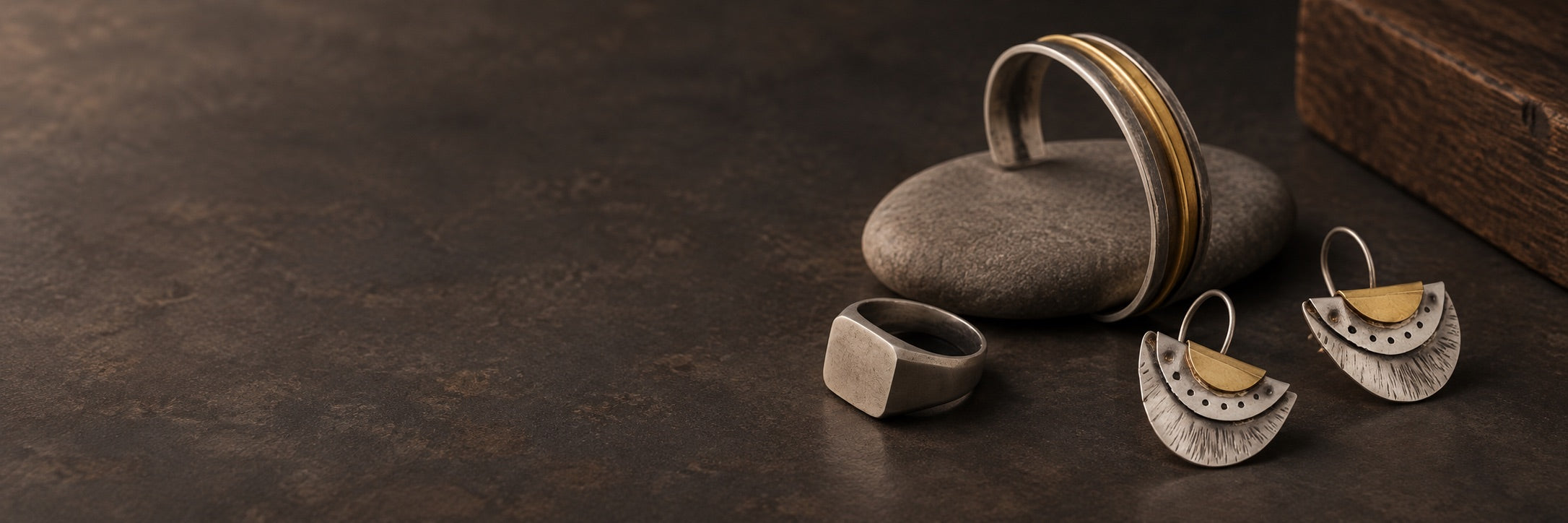 Silver signet ring, mixed-metal cuff and fan earrings on natural stone